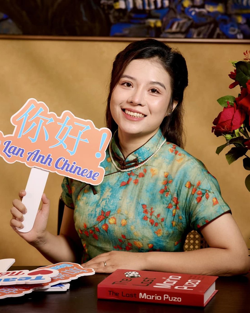 Cô Lan Anh mặc áo sườn xám, cầm biển chào 你好 Ms Lan Anh Chinese